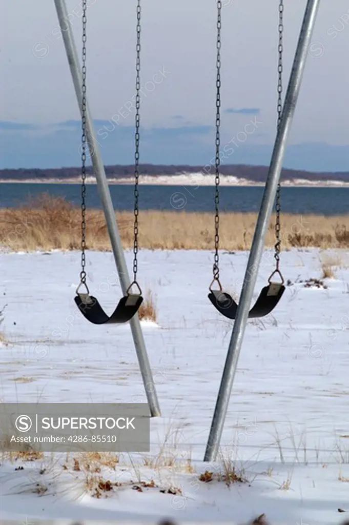 swings on a playground, in the snow, along the Great Peconic Bay, Long Island, NY