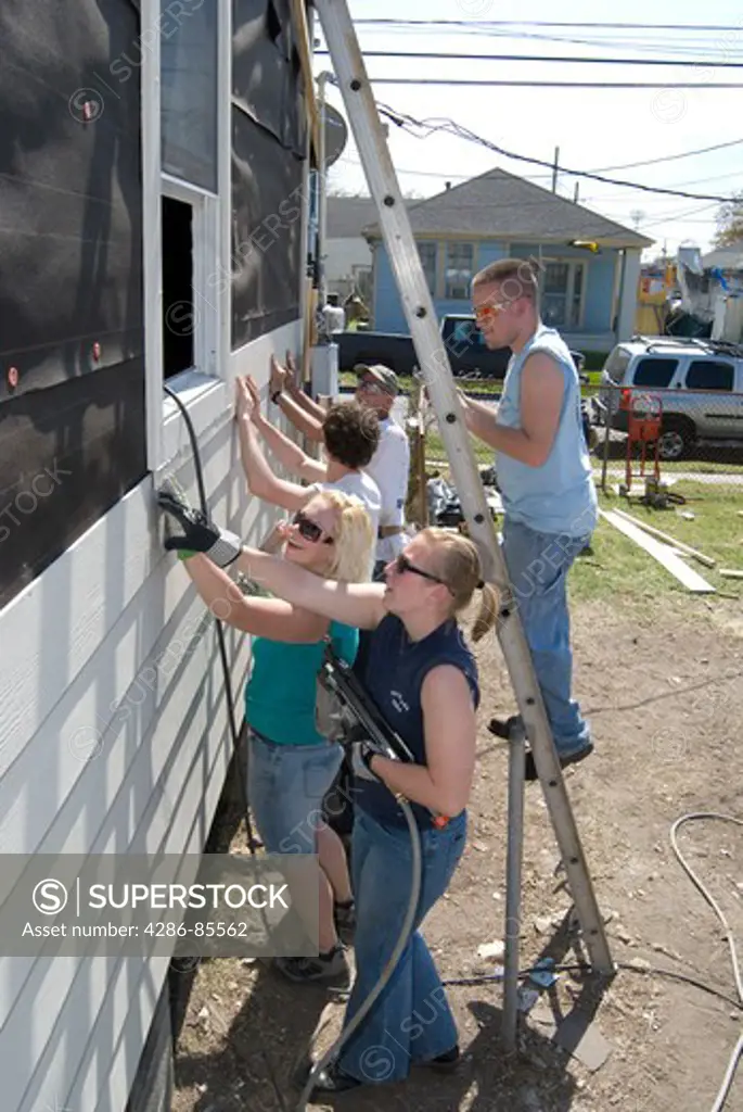 Group of young adults working and remodeling exterior of a house
