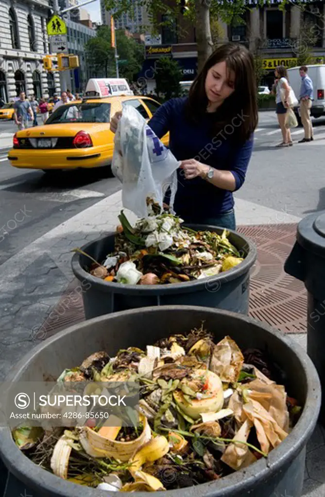 Union Square, NYC, 2009 - Young woman emptying a bag of food waste into compost heaps at an outdoor farmer's market.  Model Released - Marty Heitner