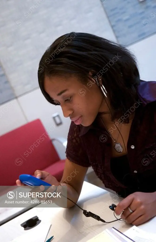 Brooklyn, NY, 2009 - college student consulting her personal listening device, while doing homework, in the school's library.  Model Released. 