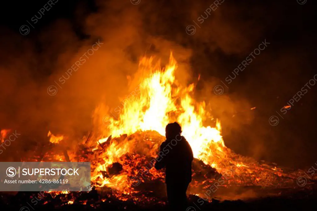 Silhouette of a man in front of a bonfire to celebrate the patron saint, Italy