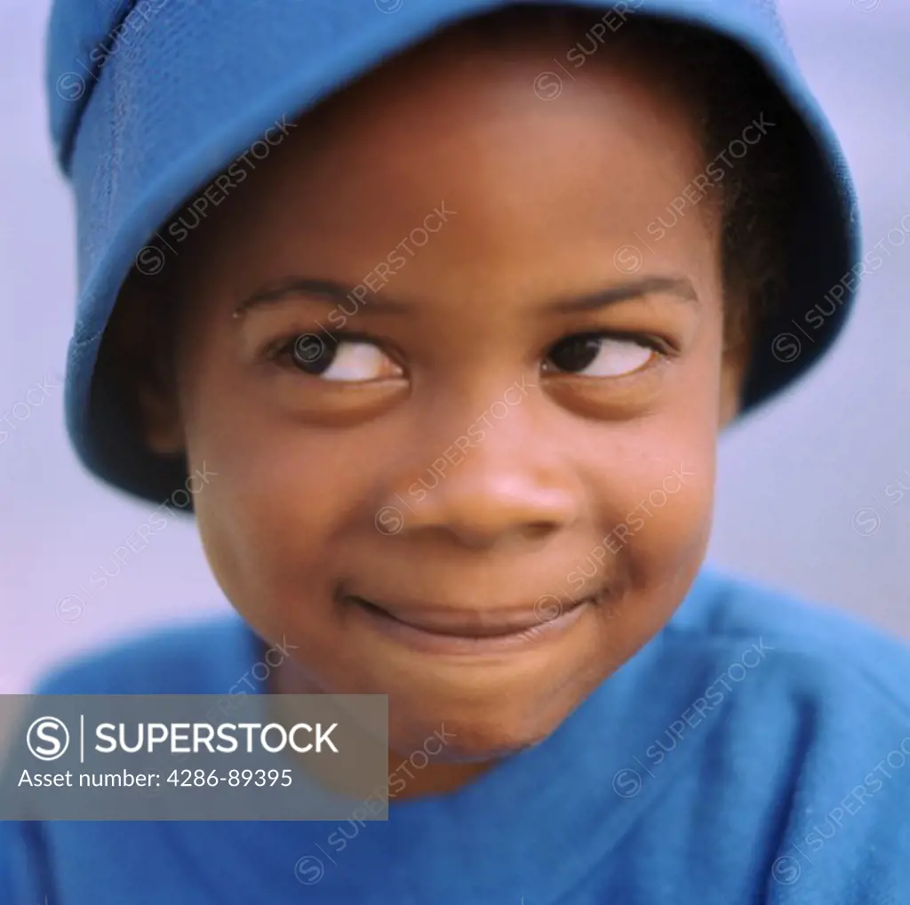 Young African American boy wearing a blue hat with his eyes wandering at an angle