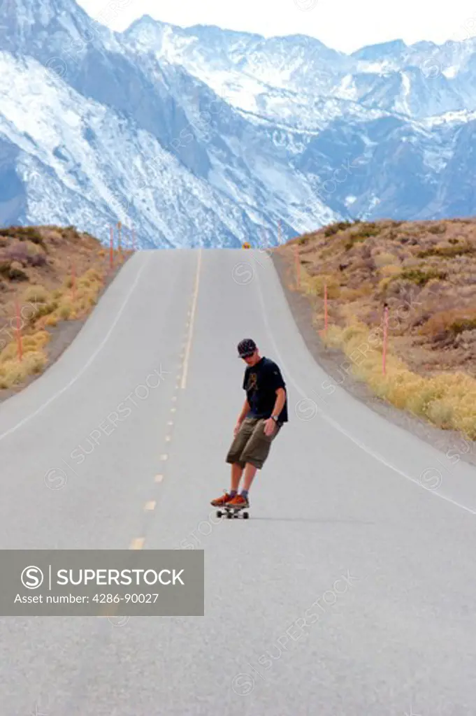 Man on skateboard going down hill in the Eastern Sierra Nevada mountains