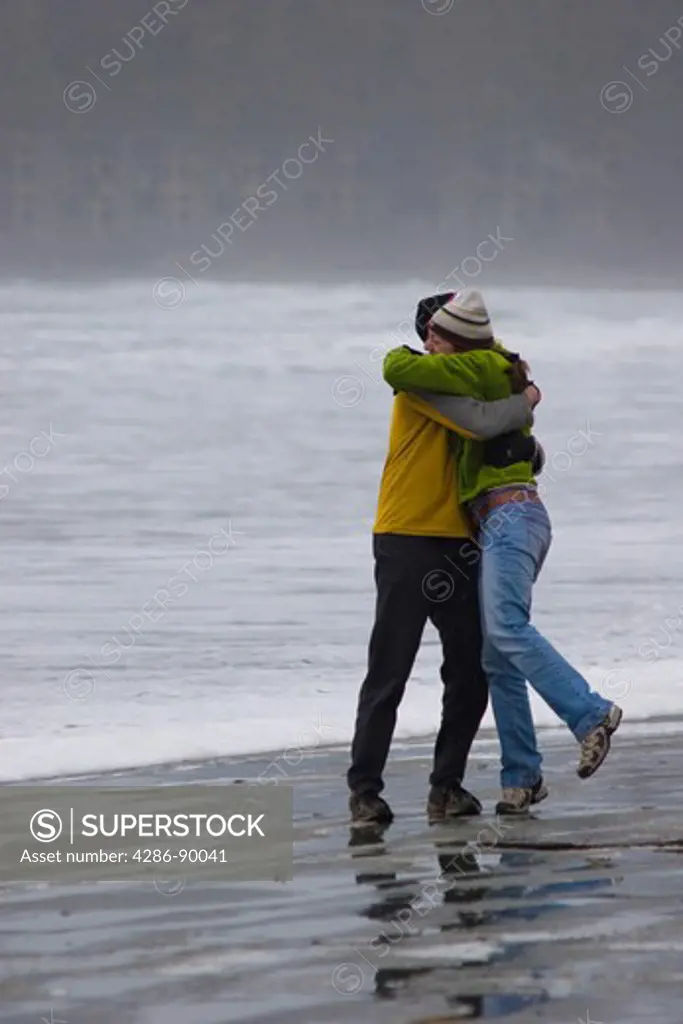 Man and woman embracing on a cool wintery beach, near Tofino, BC