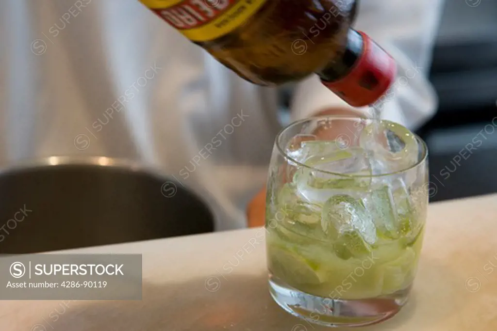 A barman pouring Cachaca into a glass to make a drink of Caipirinha, Brazil's national cocktail. 