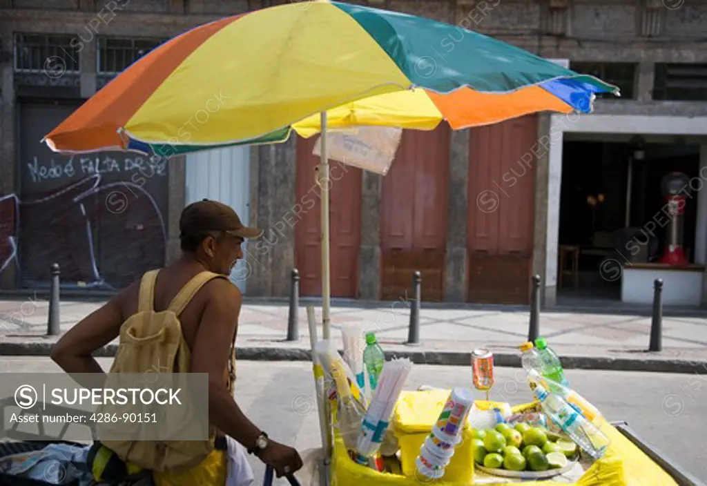 Brazil. Rio de Janeiro. Brazillian man selling soft drinks and Capirinha alcohol  from his mobile stall. Lapa district