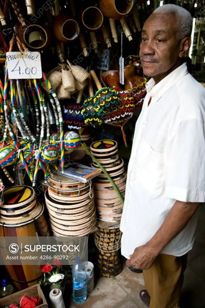 Brazil, Salvador, Bahia. Shop keeper and Musical Instruments on sale in The Mercado Modelo