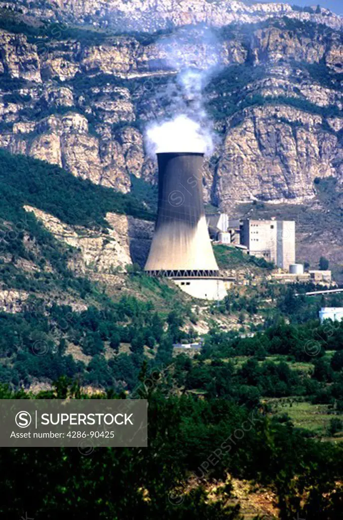 Energy. Nuclear cooling tower and plant by mountainside. S. France.