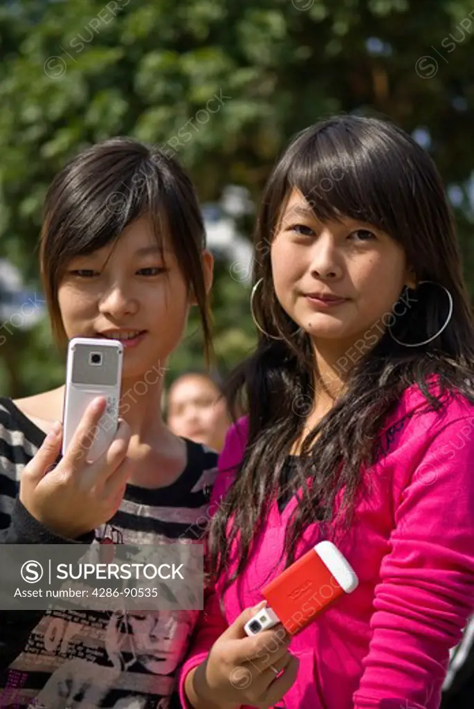 Young women with cellular phones text message, Quanzhou, Fujian Province, China