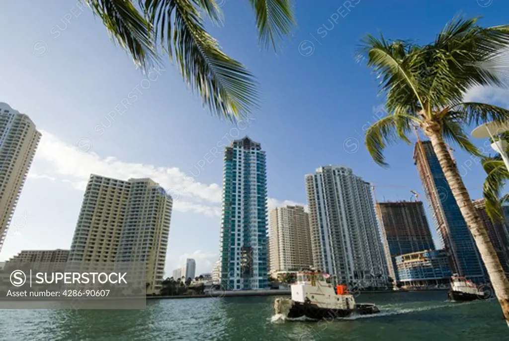 Tug boats navigate high rise building canyon along tropical Miami River at entrance to Biscayne Bay, Miami, Florida