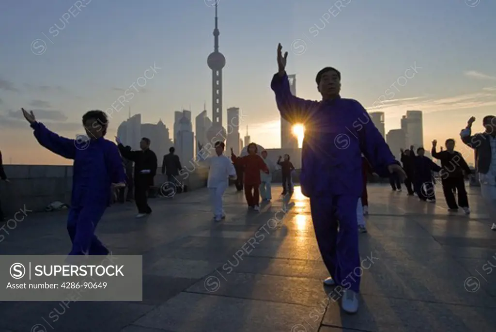 Costumed tai chi practitioners at dawn skyline, The Bund, Shanghai, China