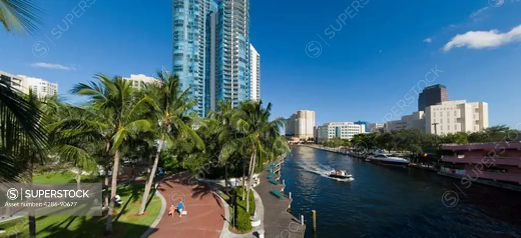 Couple strolls and boaters float along The New River walkway, downtown Fort Lauderdale, Florida