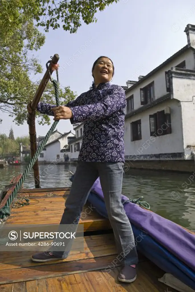 Tour guide sings folk songs as she rows traditonal canal boat of historic water town, Zhouzhuang, Jiangsu Province, China