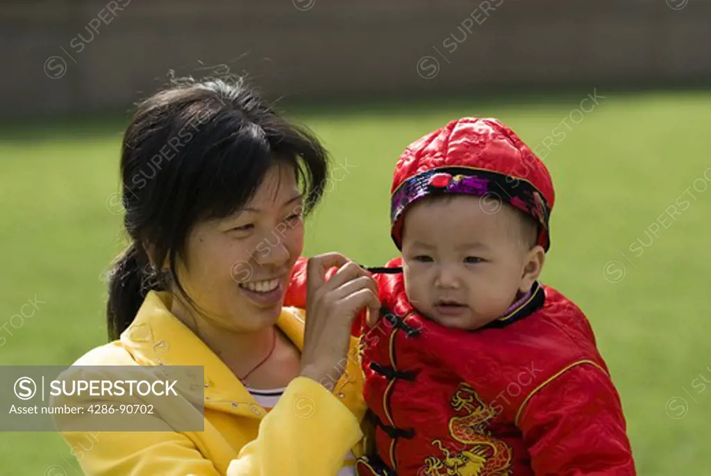 Proud mother with baby boy dressed in traditional costume, Renmin Park, Shanghai, China