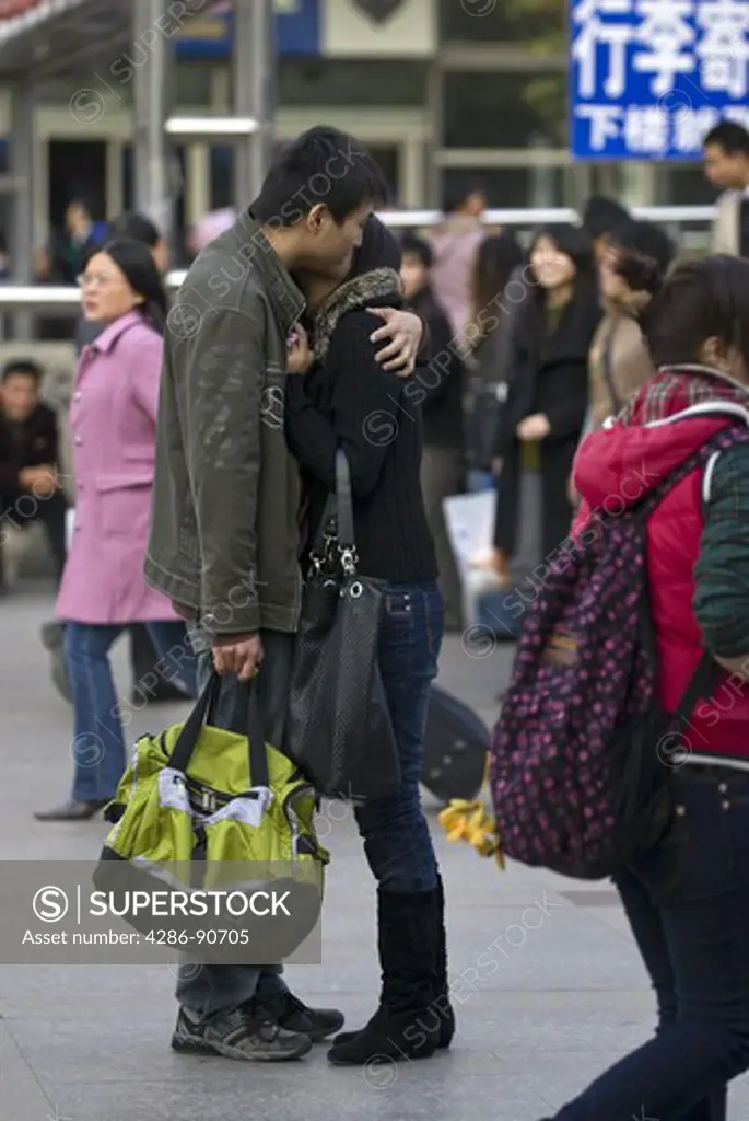 Young boyfreind and girlfriend kiss in busy train station, Shanghai, China