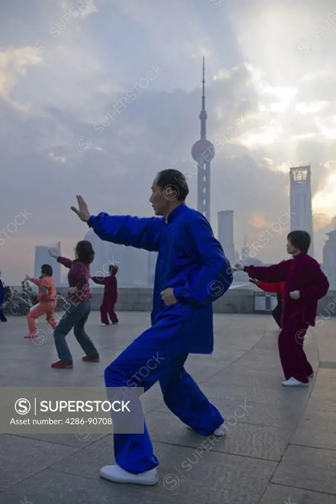 Costumed tai chi practitioners at dawn skyline, The Bund, Shanghai, China