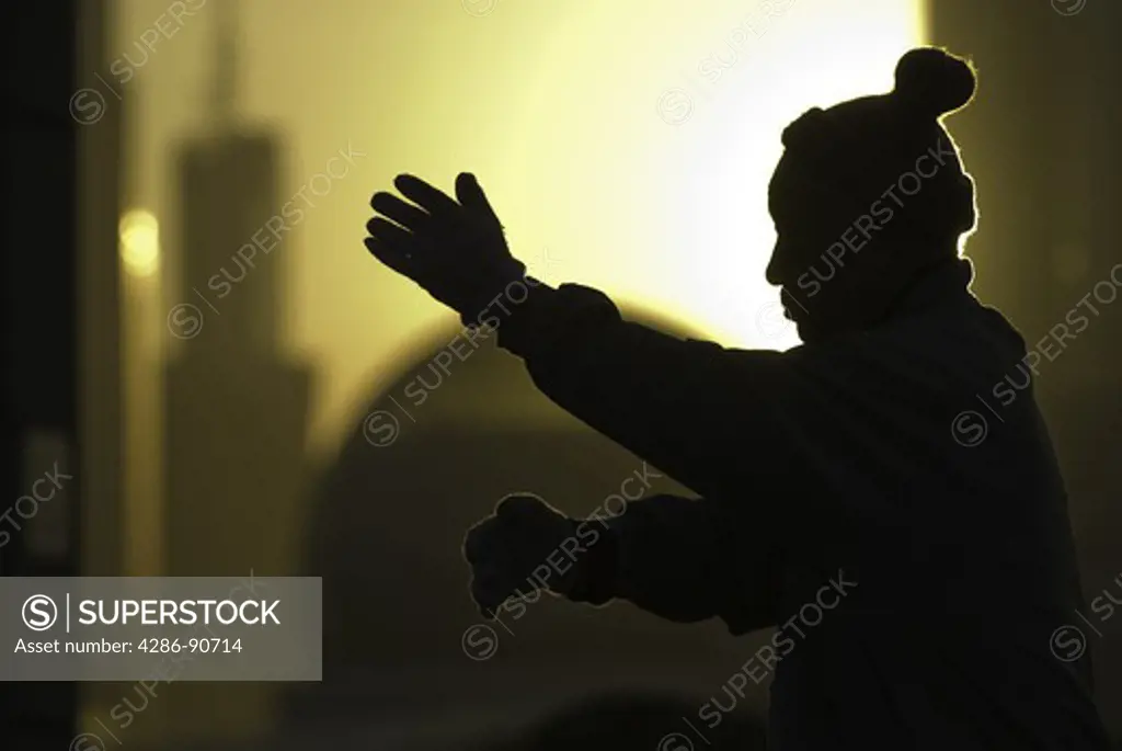 Senior man practices tai chi as sun rises over skyline, The Bund, Shanghai, China