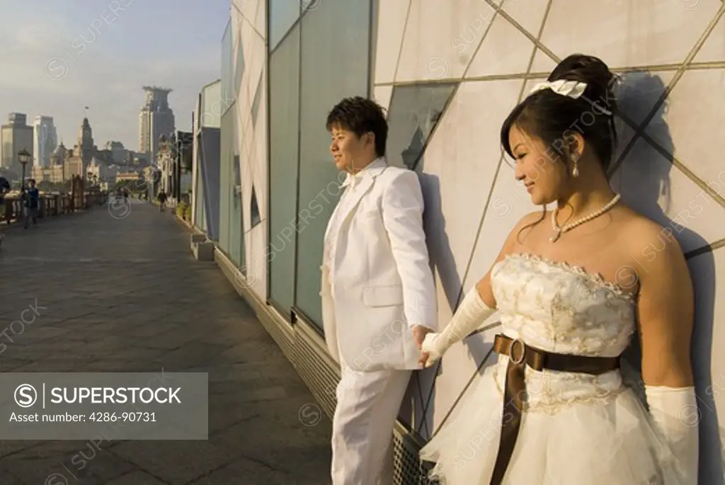 After celebrating all night young bride and groom greet sunrise on The Bund, Shanghai, China