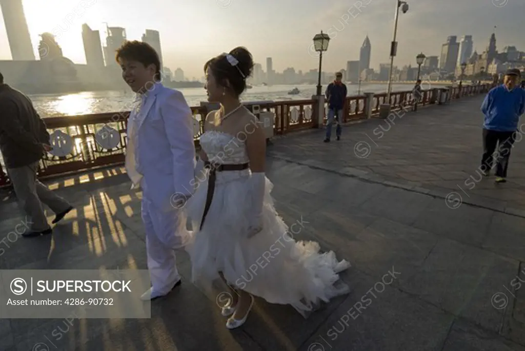 After celebrating all night young bride and groom greet sunrise on The Bund, Shanghai, China