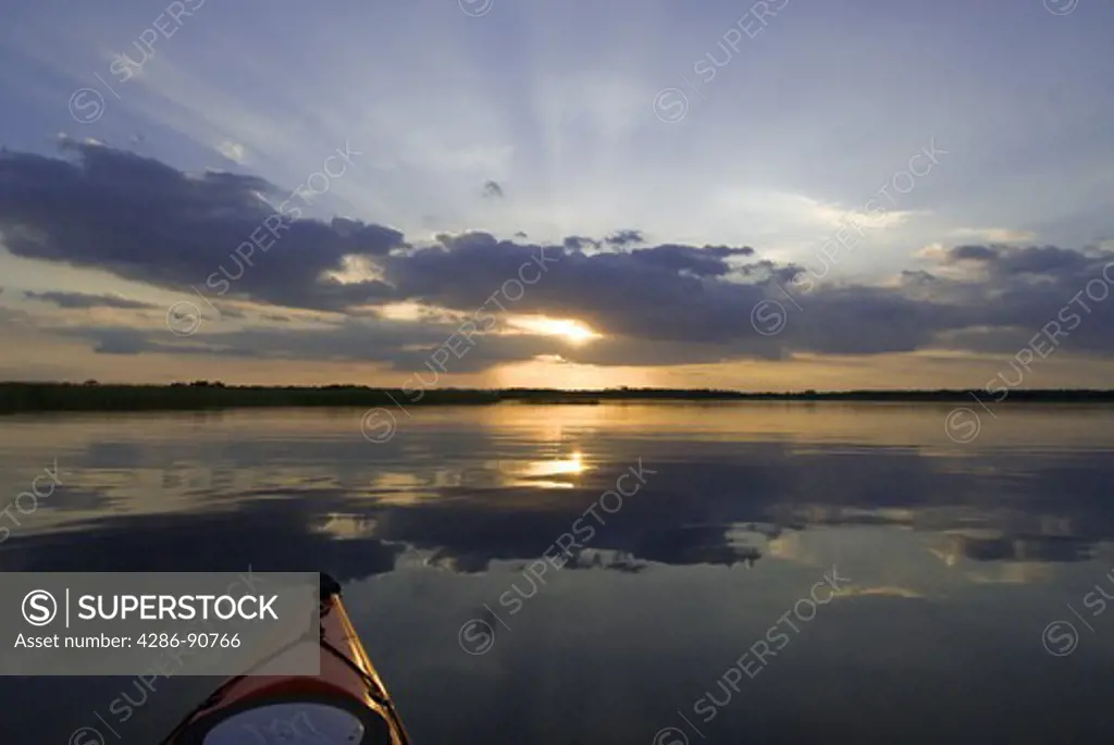 Lake reflection highlights sunset and clouds above kayak, Lake Kissimmee, Lake Kissimmee State Park, Florida