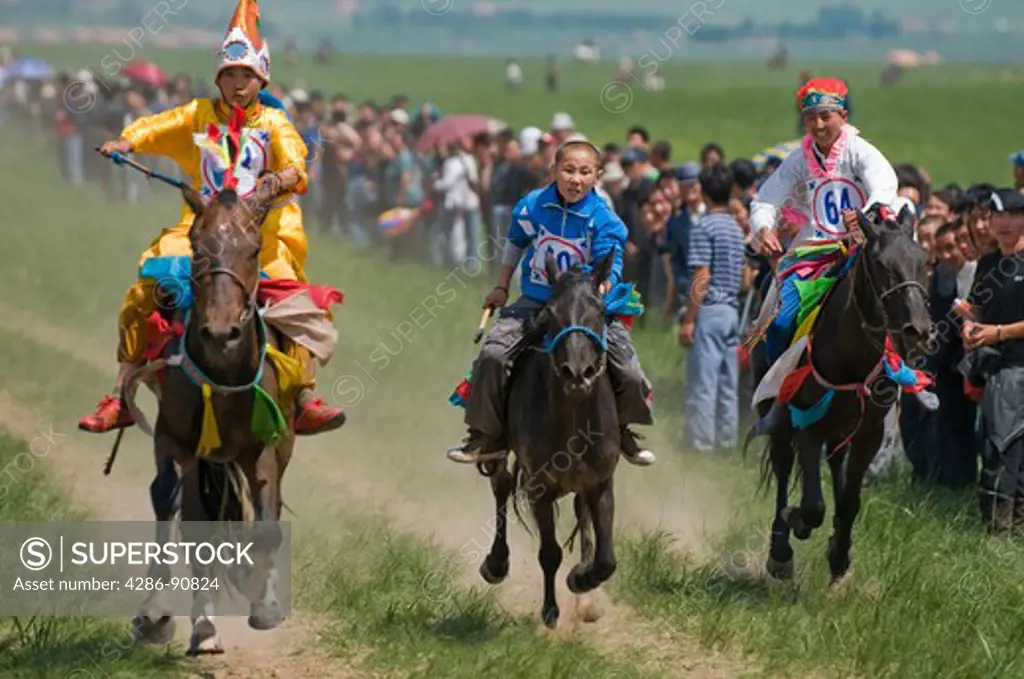 Ethnic Mongolian costumed boy jockeys race horses at summertime Naadam Festival, Xiwuzhumuqinqi, Inner Mongolia, China