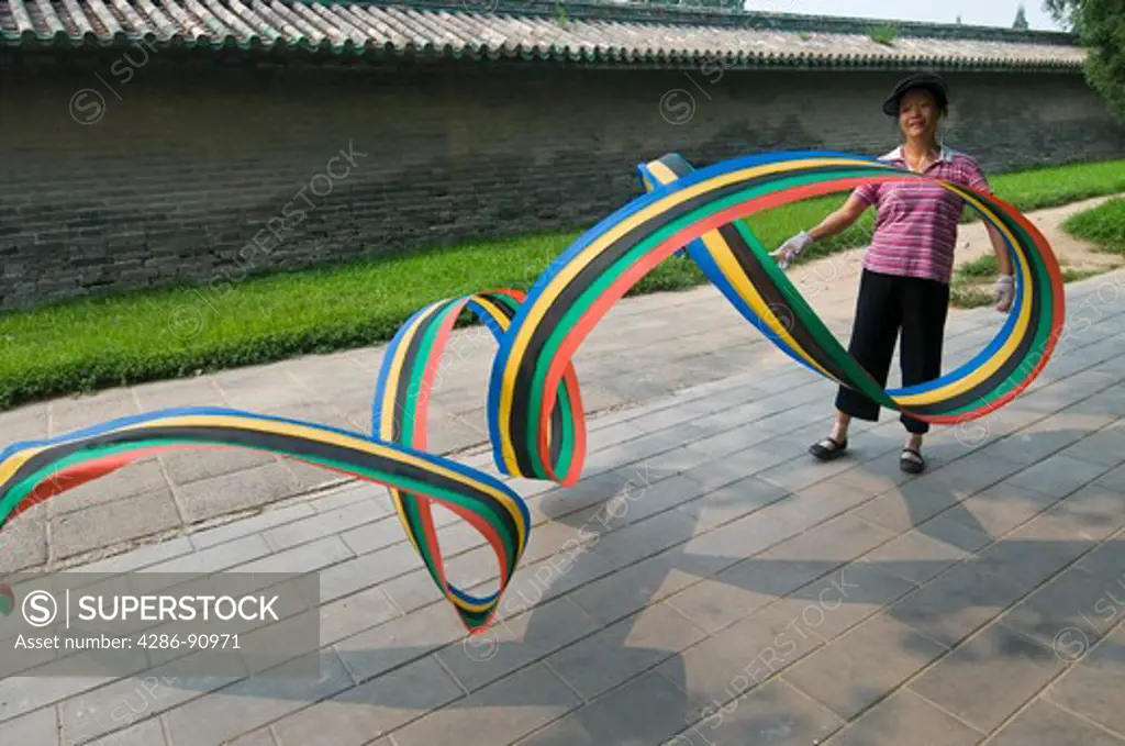 Woman does early morning exercises with twirling ribbon, Temple of Heaven, Beijing, China