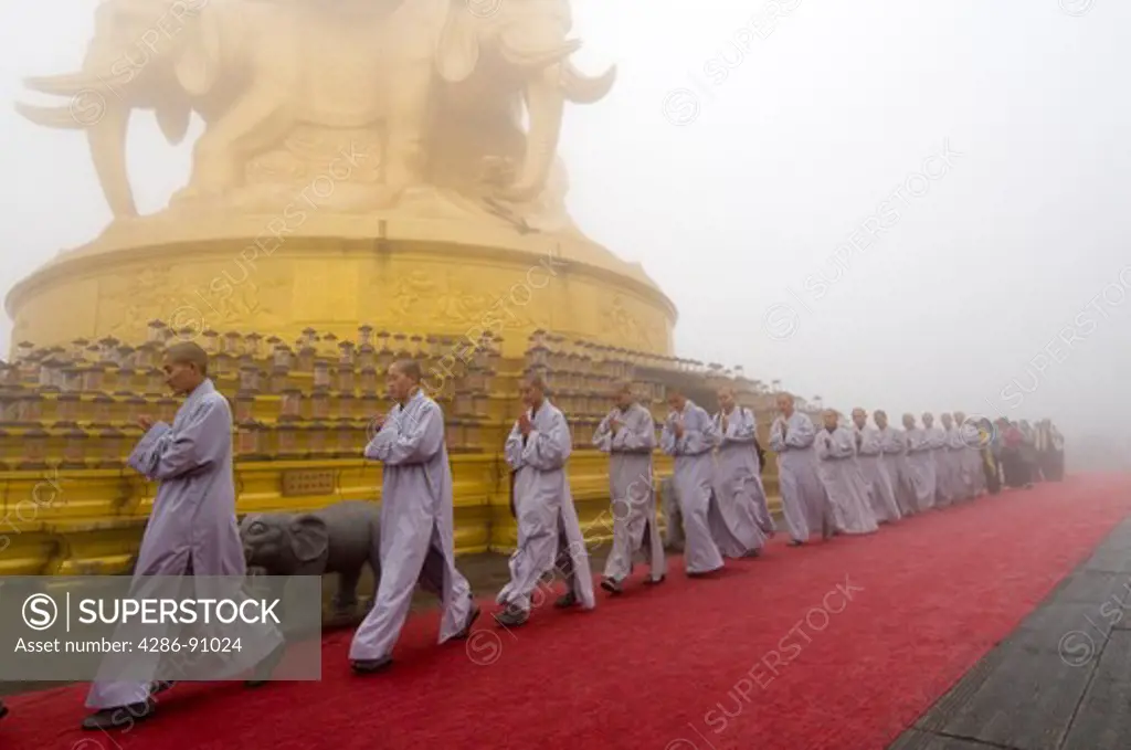 Buddhist pilgrim nuns circumambulate fog shrouded Golden Temple, Emei Shan, Sichuan Province, China