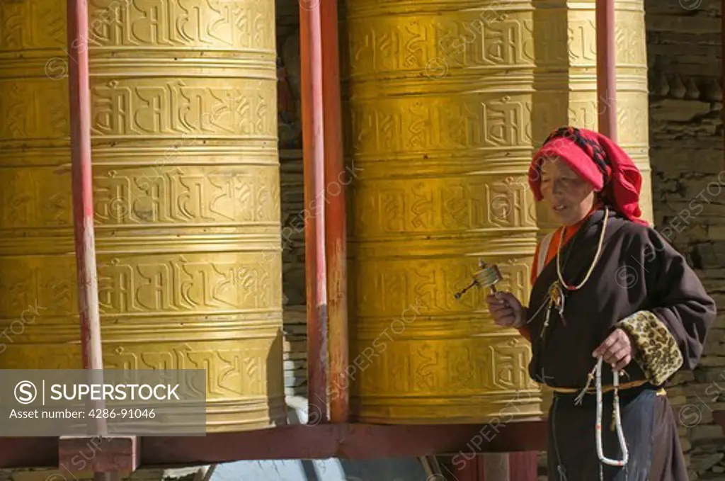 Tibetan Buddhist pilgrims turn golden prayer wheels at Huiyuan Temple, Bamei, Sichuan Province, China
