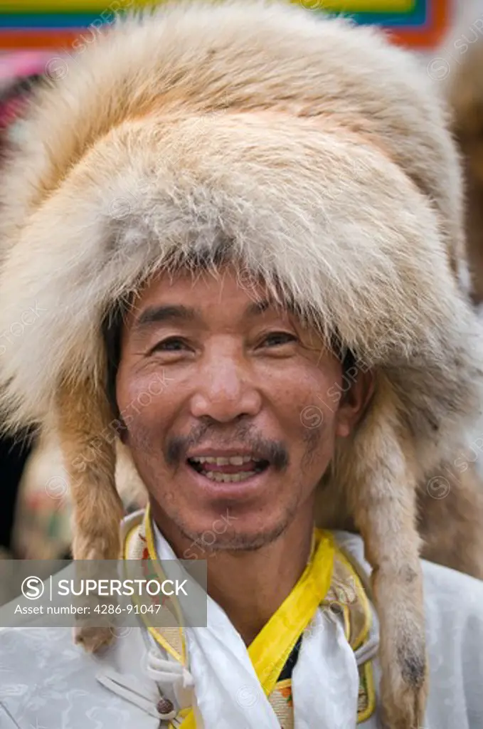 Ethnic Tibetan male dancers wear animal fur hats wait to perform at folk festival, Danba, Sichuan Province, China
