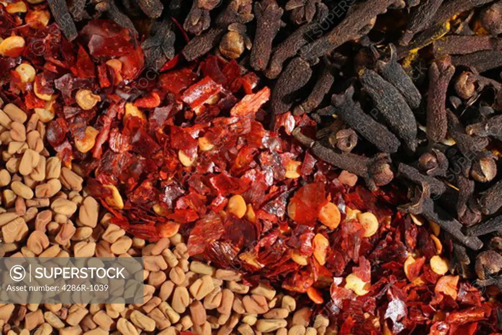 A macro view of fenugreek, crushed chilles and cloves for a background