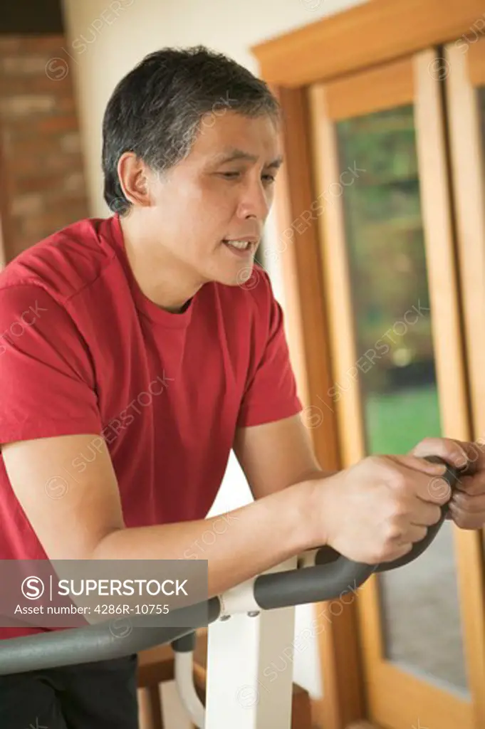 Senior Asian man on exercise stepper machine.  PR