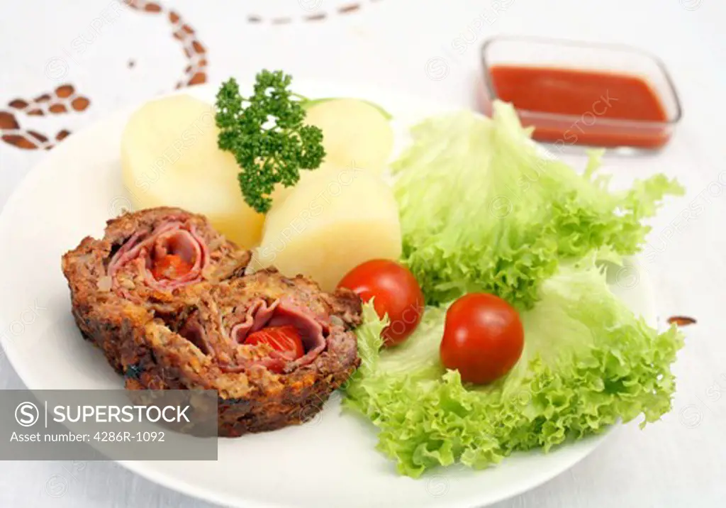 Beef roulade (rolled beef meatloaf) containing ham and cherry tomatoes, served with lettuce,boiled potato,cherry tomatoes and a tomato dip.