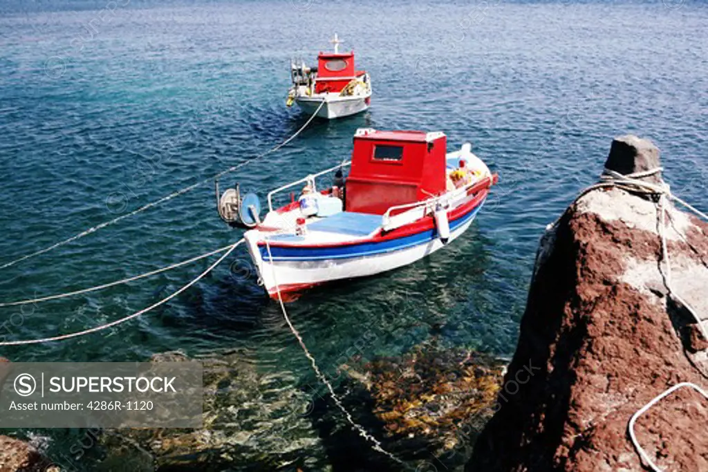 Two small fishing boats tied-up by the shore at Akrotiri, on the southern side of Santorini, Greece.