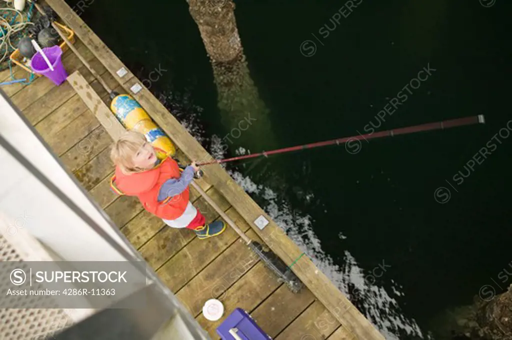 3 year old girl fishing on a dock, Bull Harbour. British Columbia, Canada.MR-0501
