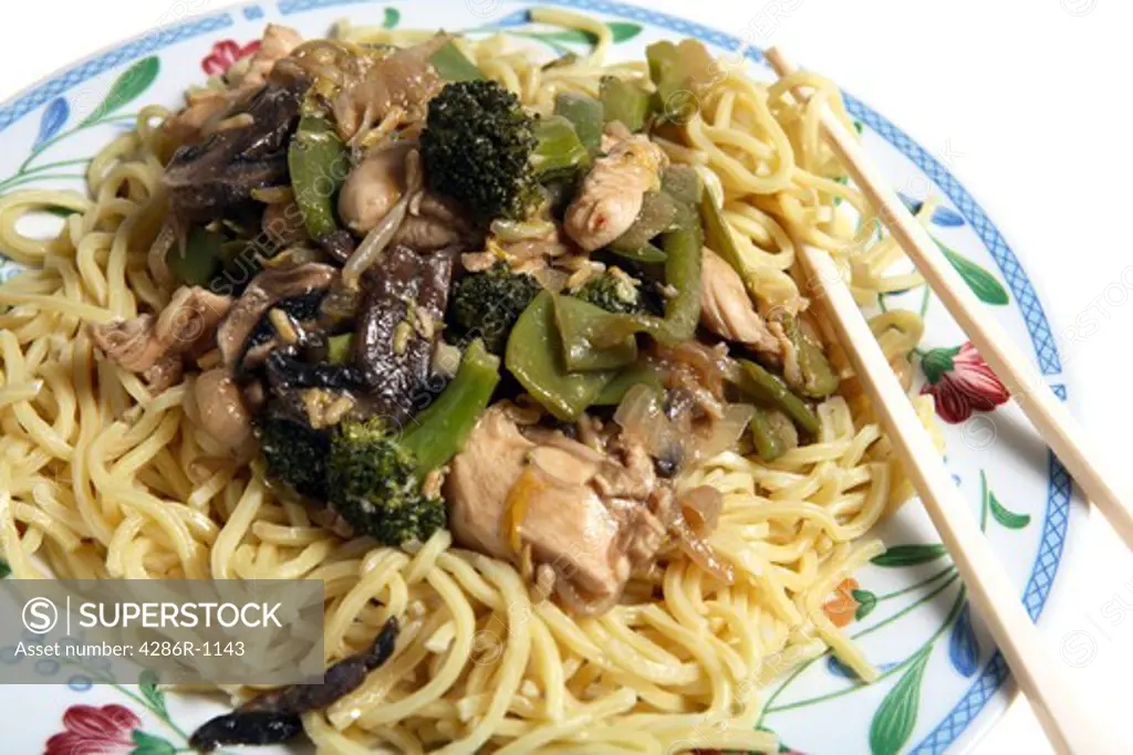 A plate of chicken chow mein (cantonese egg noodles) with chopsticks.