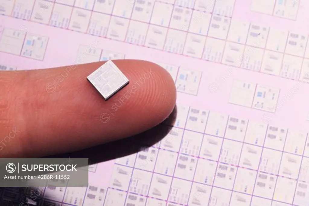 Microchip on finger. IC wafer background.