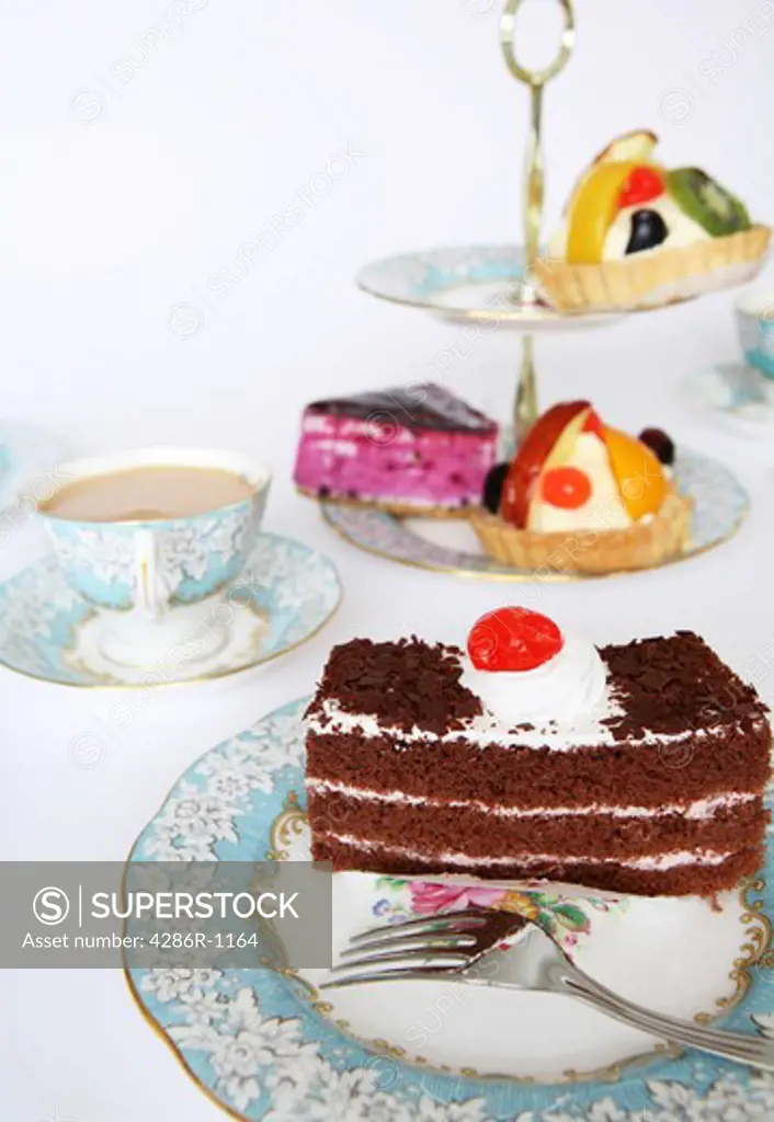 A slice of chocolate cake tempting the palate at teatime. Other cakes are offered on the traditional cake-stand.