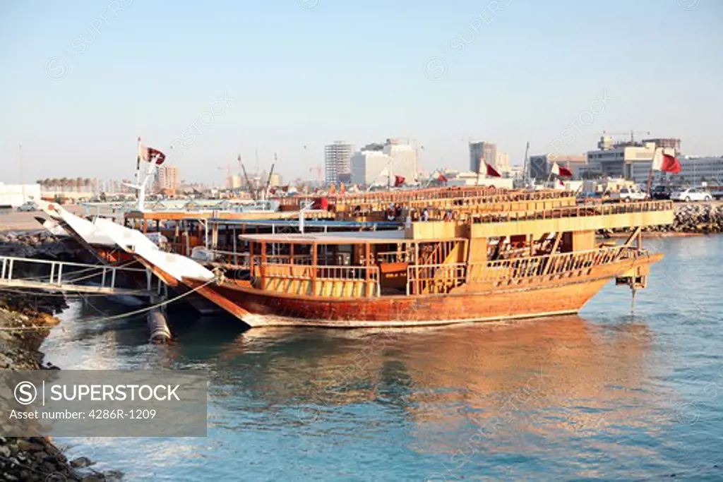 A row of Qatari dhows tied up in the Dhow Harbour, Qatar, waiting to be hired out for pleasure trips