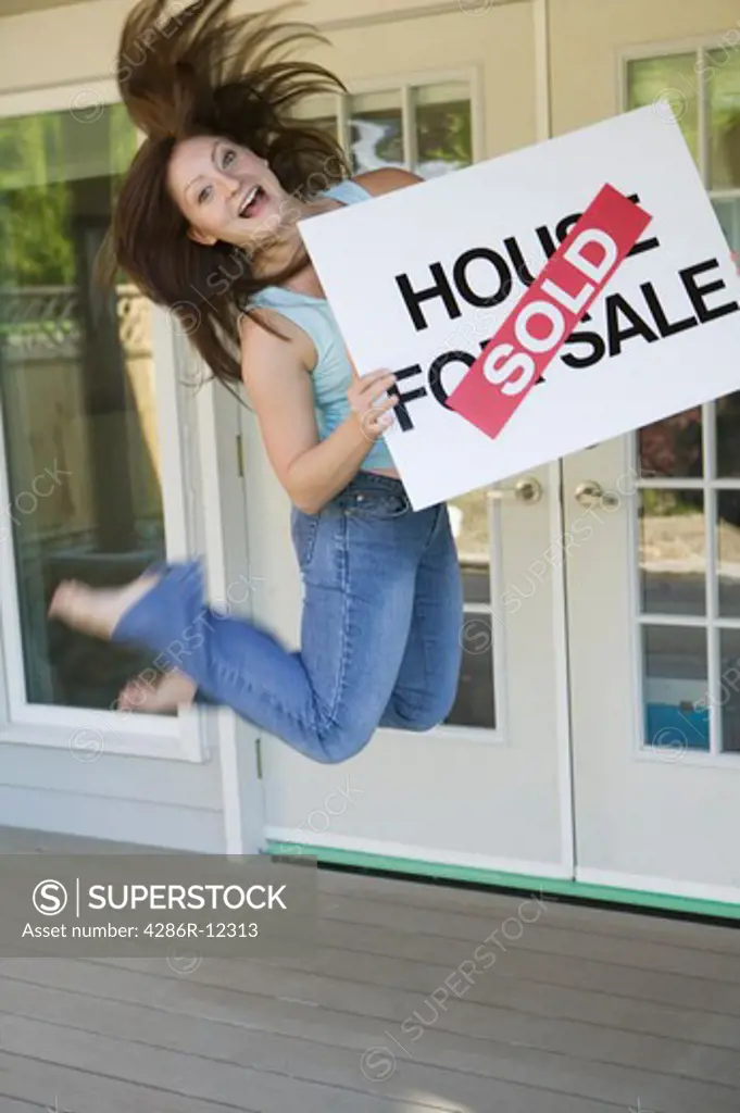 Woman Jumping For Joy With a House For Sale Sold Sign