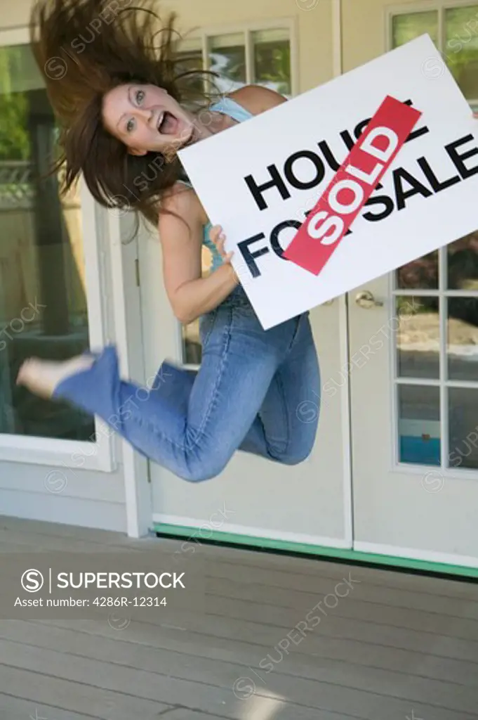 Woman Jumping For Joy With a House For Sale Sold Sign