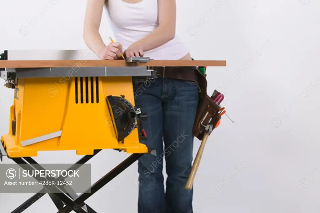 Woman Standing Beside a Table Saw Measuring a Piece of Wood, MR-0636