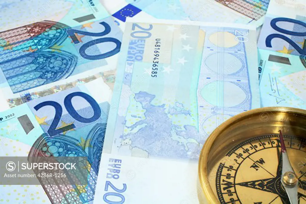A compass, showing North, on a background of 20 euro banknotes - symbolic of finances being on the right course.