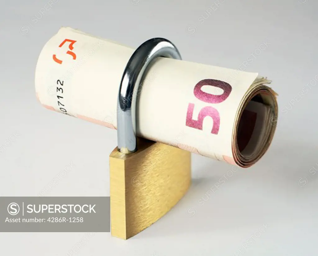 A roll of 50 euro notes in a closed padlock, symbolising financial security. Diagonal depth of field to keep the notes in focus across the image.