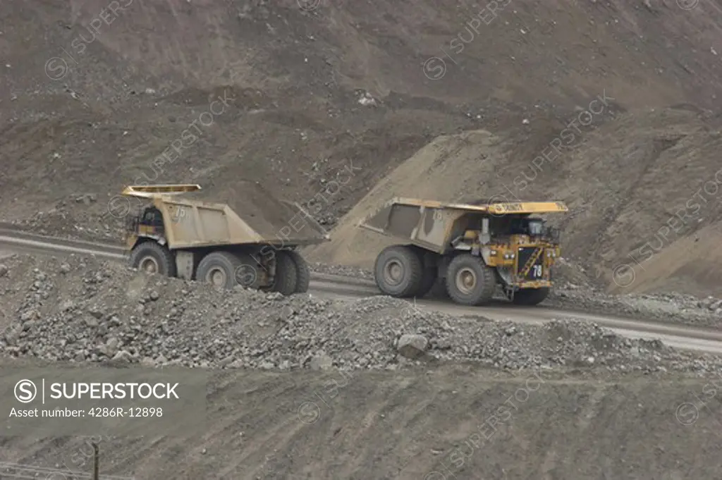 Two huge dump trucks pass by each other at Highland Valley Copper mine