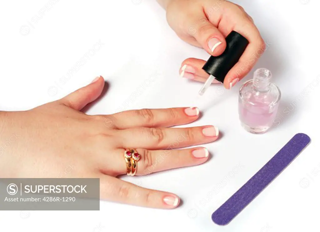A young woman applying varnish to French polished nails