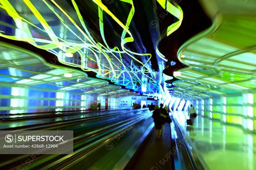 Abstract image of people on moving sidewalks with neon lights overhead