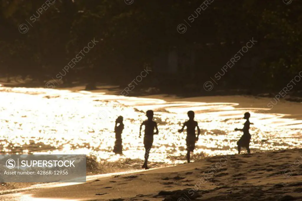 High contrast image of young children running in the warm surf at sunset Bequia