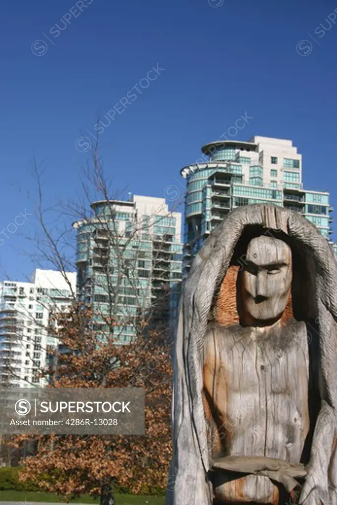 Native wood carving with modern glass buildings behind