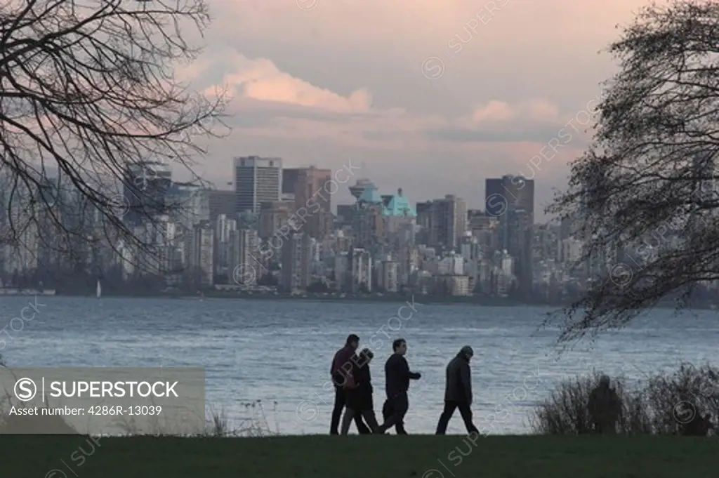 Four afternoon walkers along the waterfront with Vancouver Skyline behind