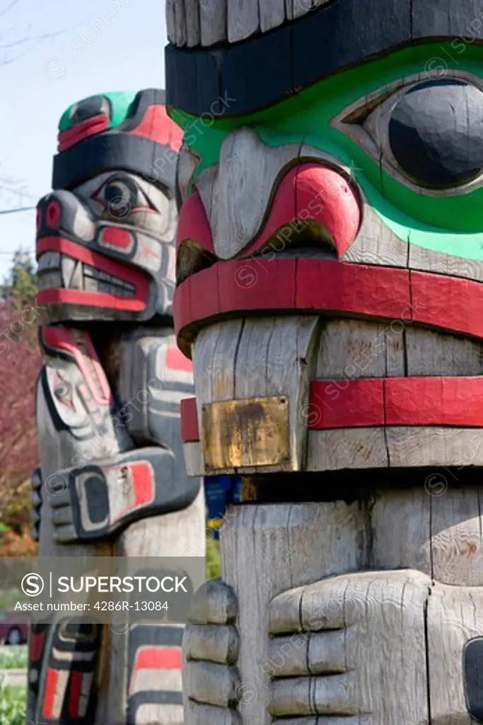 Closeup of two colorful totem poles in Duncan, Cowichan Valley, BC. In one a bear is holding a seal.
